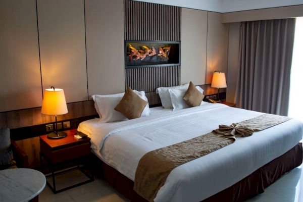 A well-organized hotel room with a large bed, soft lighting from lamps, a stylish wall feature, and a window with curtains.