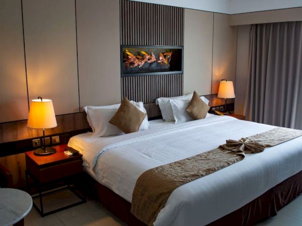 A well-organized hotel room with a large bed, soft lighting from lamps, a stylish wall feature, and a window with curtains.
