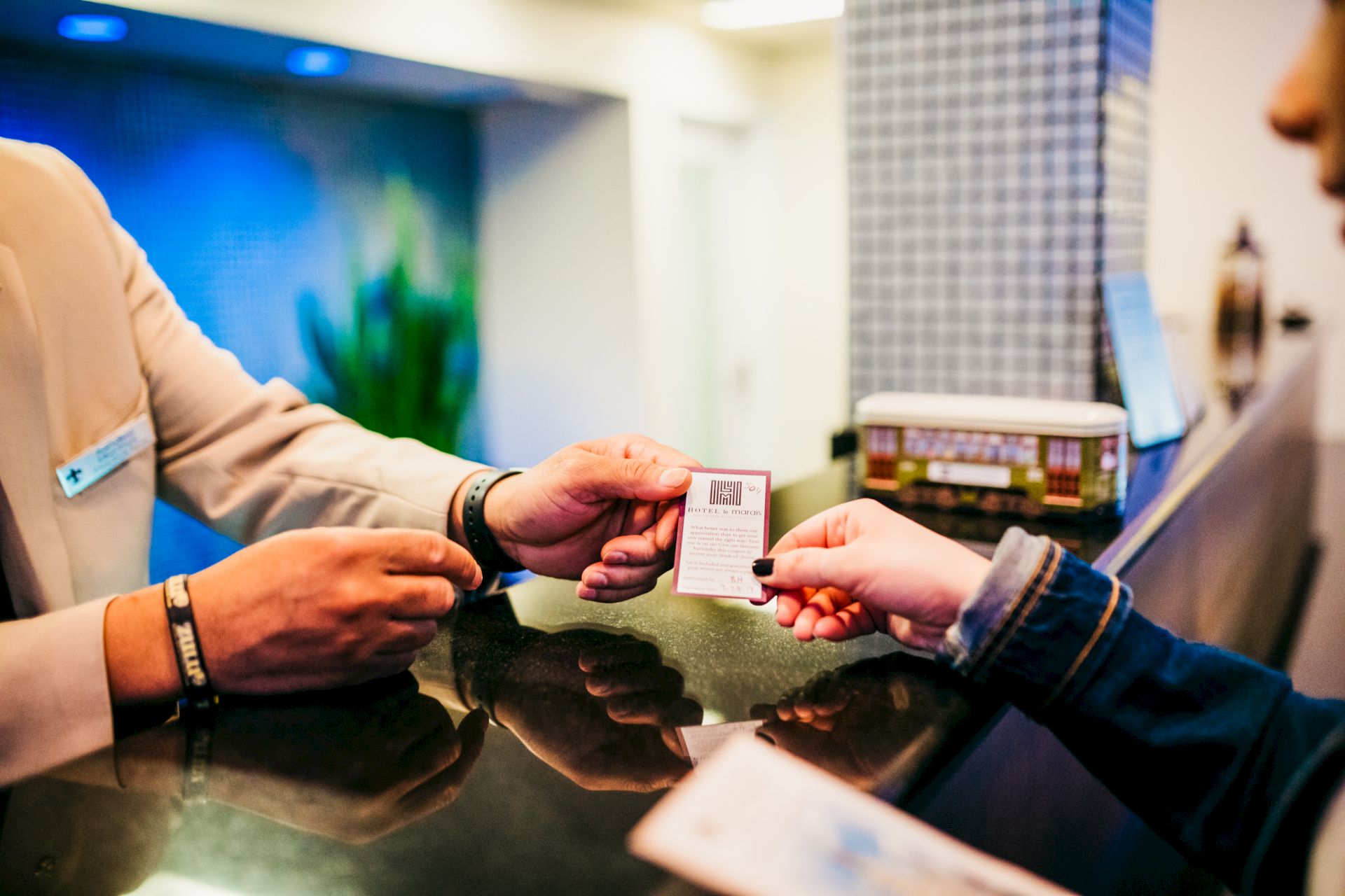 A person hands a card to a receptionist across a counter, with a model tram in the background.