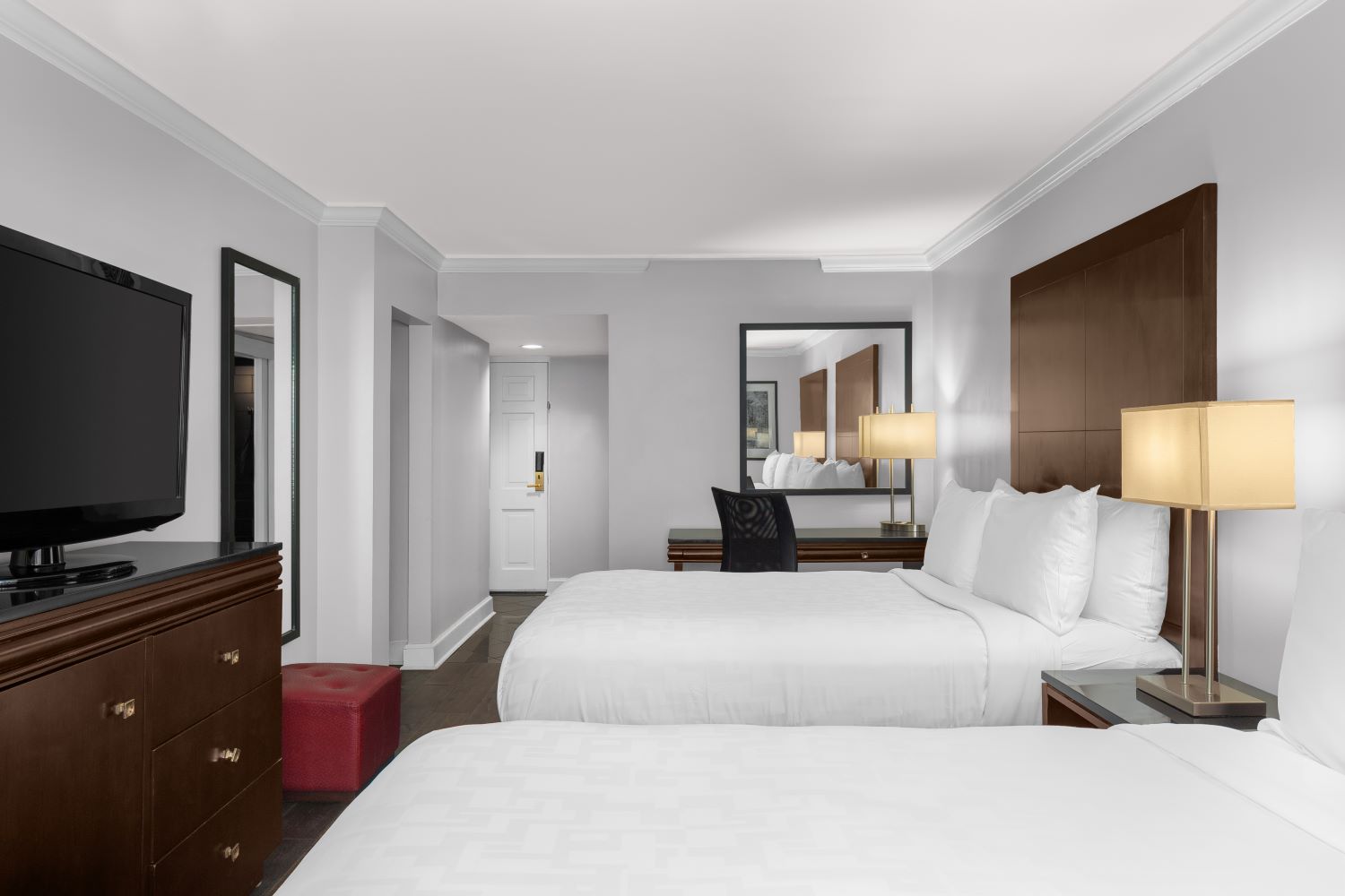 A hotel room with two beds, a dresser, nightstand, and TV