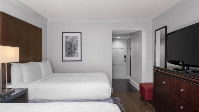 A hotel room with a bed, dresser, TV, and lamp.