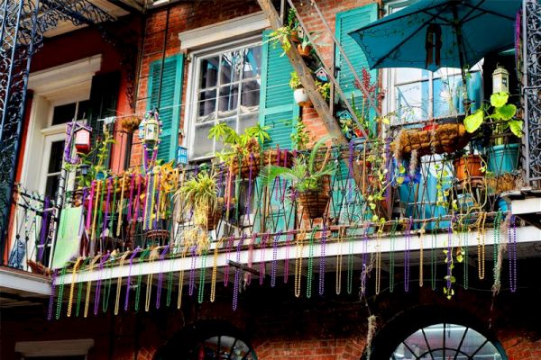 A festive balcony with plants, colorful beads, and a blue umbrella.