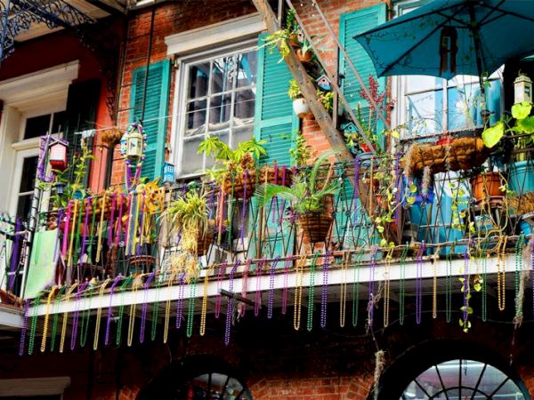A festive balcony with plants, colorful beads, and a blue umbrella.