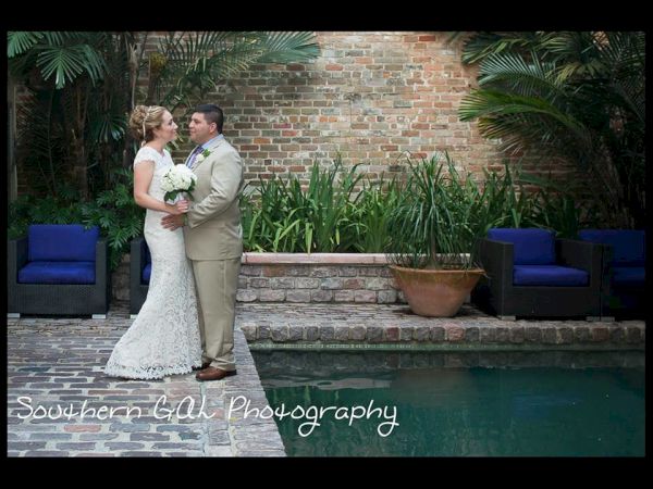 A couple in wedding attire stands by a pool, surrounded by greenery and brick walls, with "Southern Gal Photography" on the image.